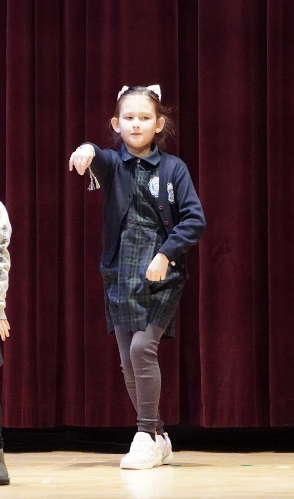 Third grader Jiah Lipsky delivers a poised and expressive performance on stage. Her focused movements and strong presence showcase her dedication to the routine, making her shine in the spotlight.